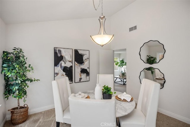 carpeted dining space with vaulted ceiling