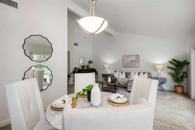 dining space featuring lofted ceiling with beams and light carpet