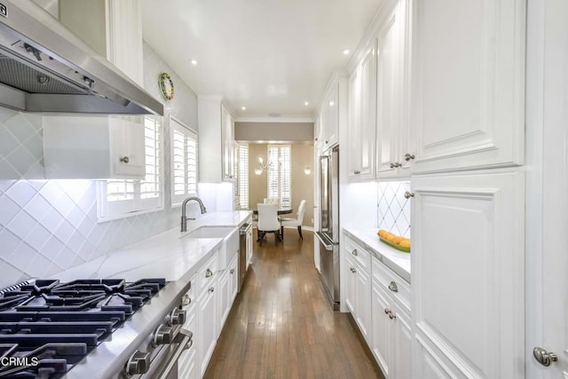 kitchen featuring appliances with stainless steel finishes, dark hardwood / wood-style floors, white cabinetry, light stone countertops, and wall chimney exhaust hood