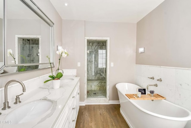 bathroom featuring vanity, wood-type flooring, plus walk in shower, and tile walls