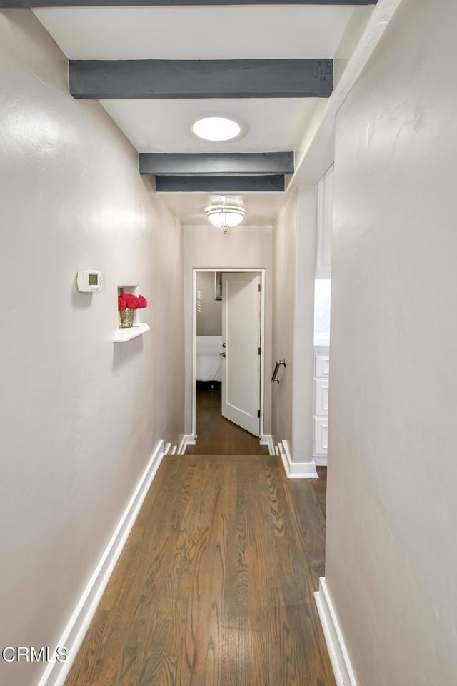 corridor featuring beamed ceiling and dark hardwood / wood-style floors