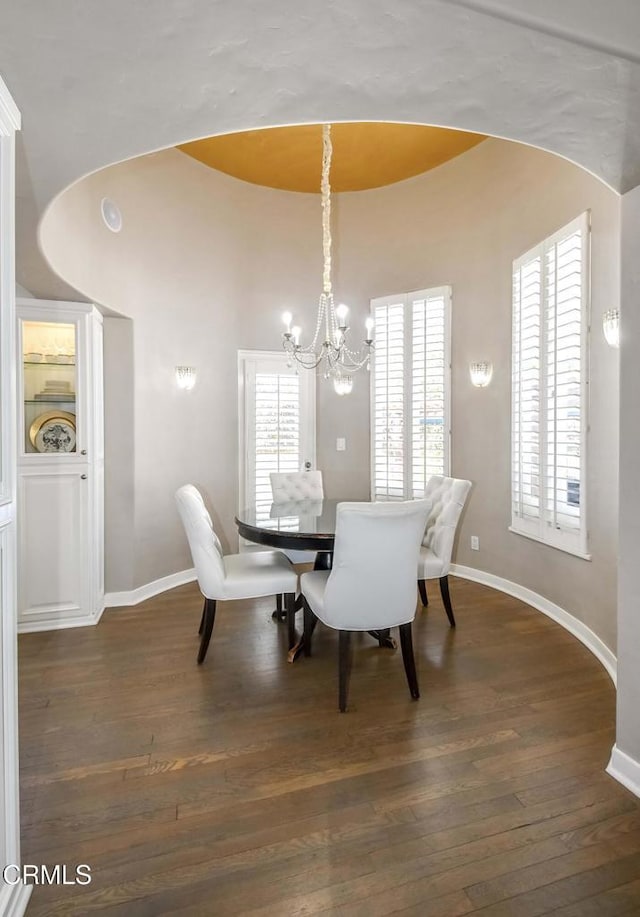 dining area featuring a notable chandelier, a wealth of natural light, and dark hardwood / wood-style floors