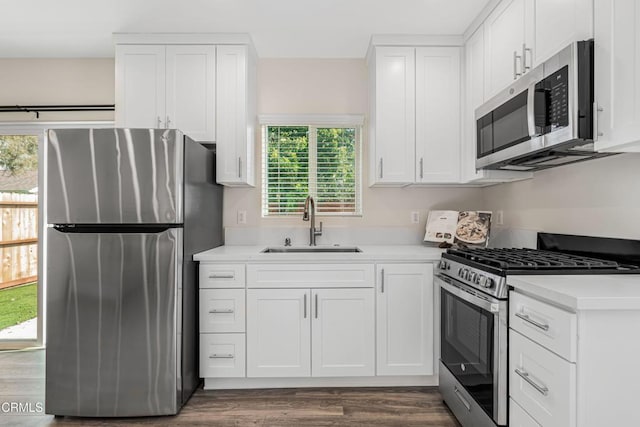 kitchen featuring stainless steel appliances, white cabinetry, sink, and dark hardwood / wood-style flooring