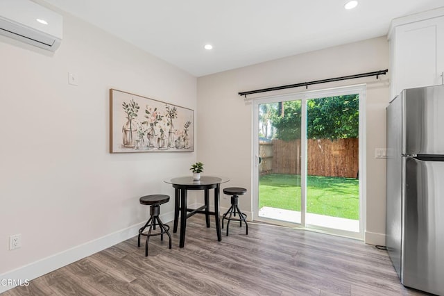 dining space with a wall unit AC and light hardwood / wood-style flooring