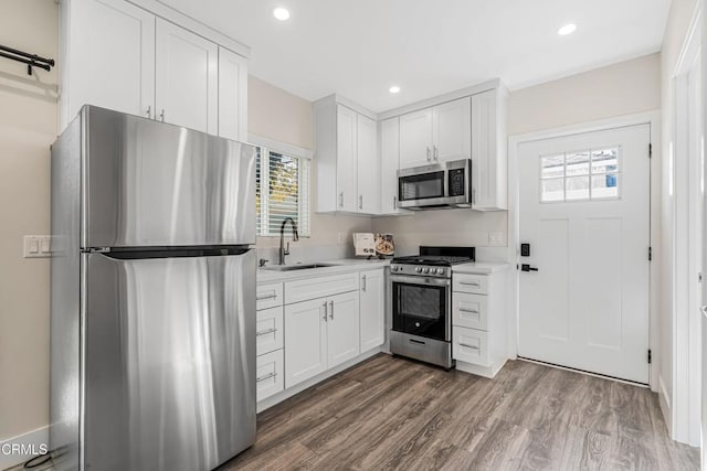 kitchen with stainless steel appliances, white cabinetry, sink, and dark hardwood / wood-style floors