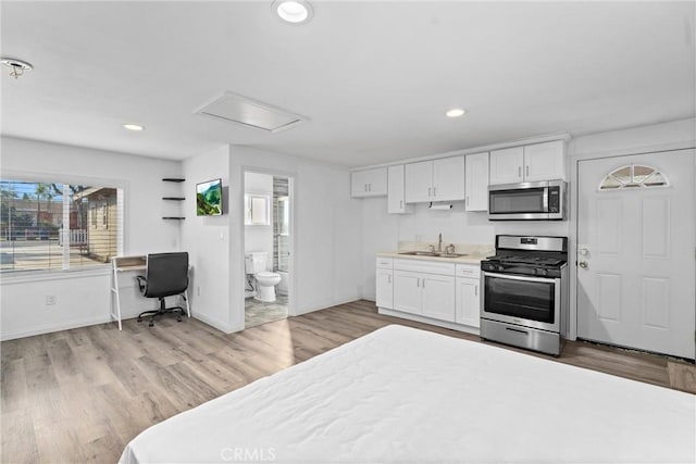 kitchen featuring light wood-type flooring, appliances with stainless steel finishes, sink, and white cabinets