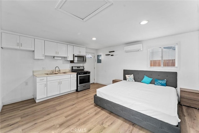 bedroom with a wall mounted air conditioner, light hardwood / wood-style floors, and sink