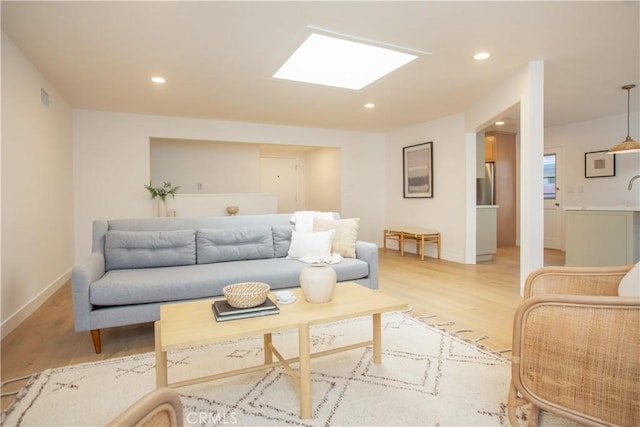 living room with light hardwood / wood-style floors and a skylight