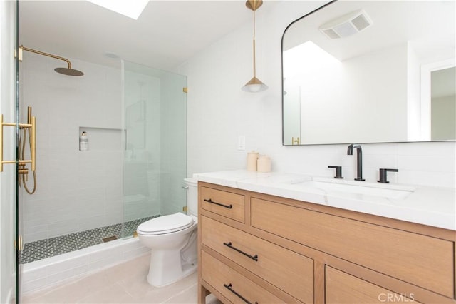 bathroom featuring a shower with door, tasteful backsplash, vanity, tile patterned floors, and toilet