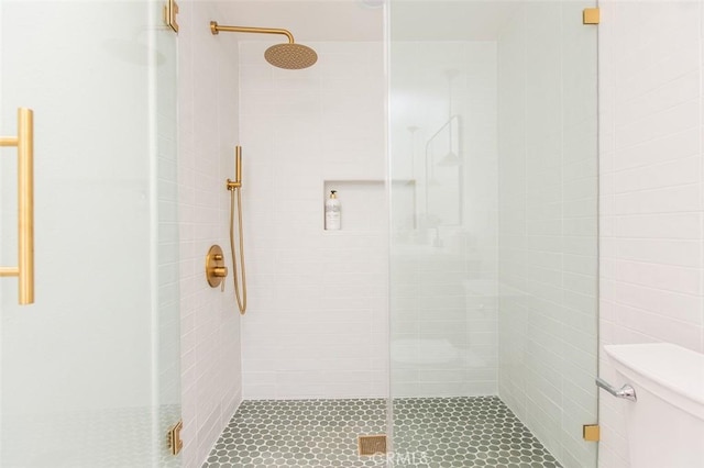 bathroom featuring toilet and a shower with shower door