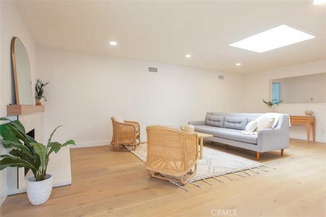 living area with light wood-type flooring, a skylight, visible vents, and recessed lighting