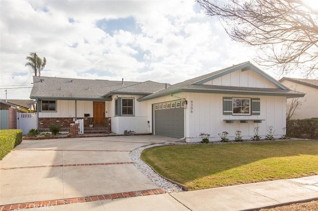 view of front of house with driveway, an attached garage, fence, a front lawn, and board and batten siding