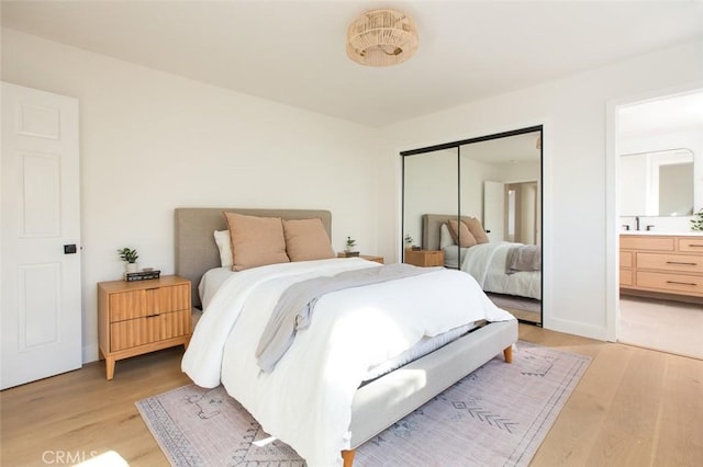 bedroom featuring sink, connected bathroom, light hardwood / wood-style floors, and a closet