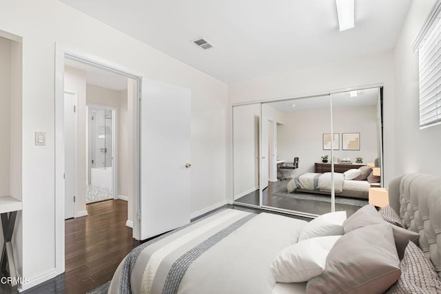 bedroom with a closet, visible vents, wood finished floors, and baseboards