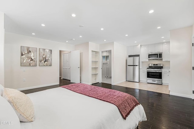 bedroom with light wood-style flooring, freestanding refrigerator, and baseboards