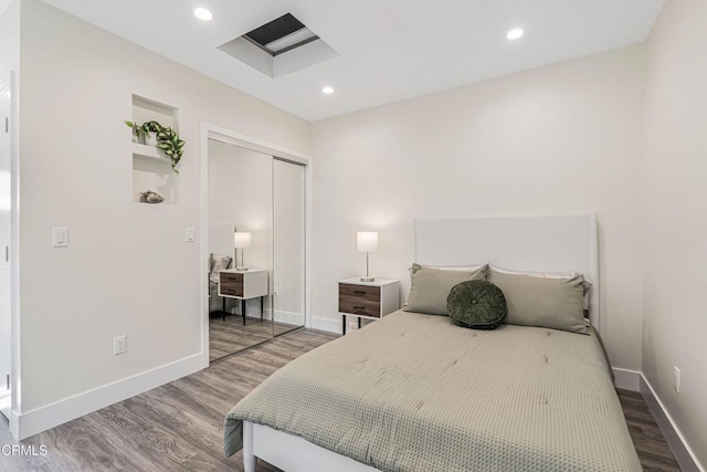 bedroom featuring baseboards, recessed lighting, wood finished floors, and a closet