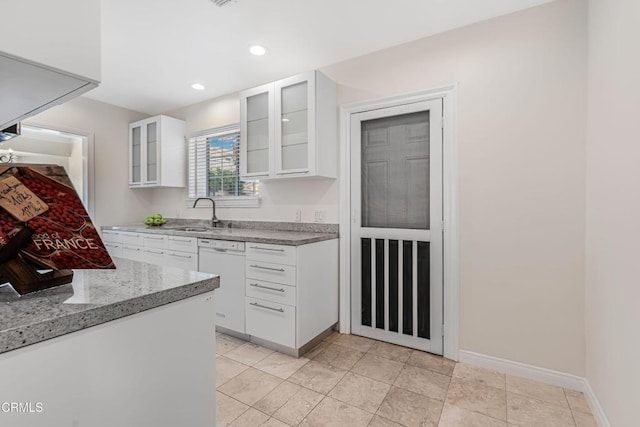 kitchen with white cabinets, a sink, glass insert cabinets, and white dishwasher