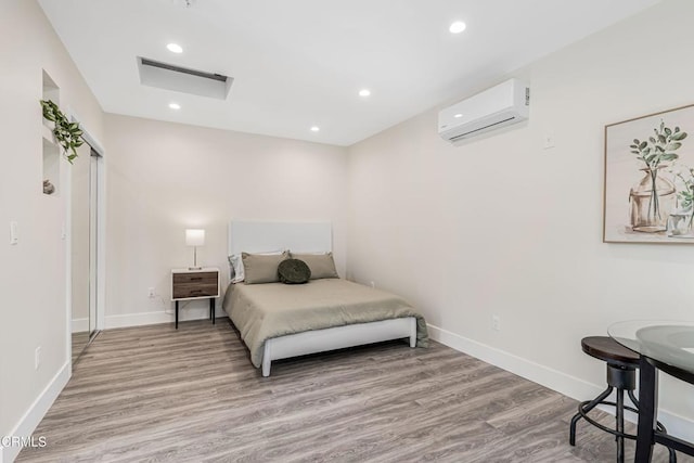 bedroom with a wall mounted air conditioner, recessed lighting, baseboards, and light wood-type flooring