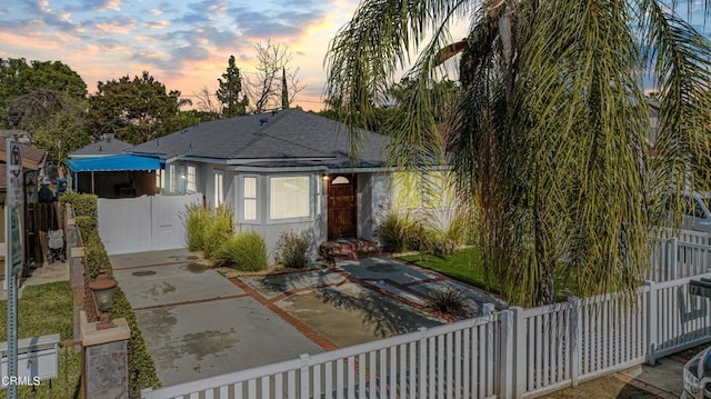 view of front of home with roof with shingles, a patio area, and fence private yard