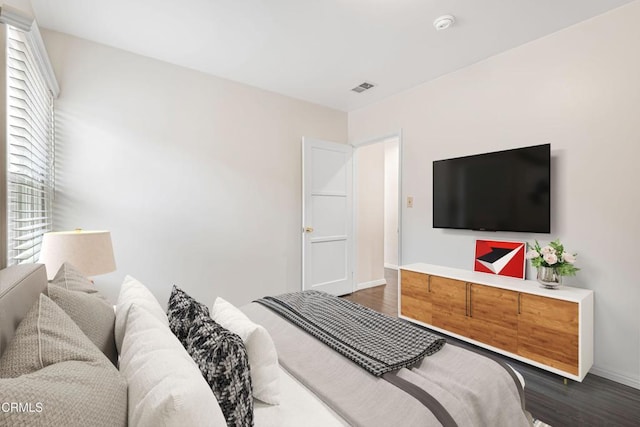 bedroom with dark wood finished floors, visible vents, and baseboards