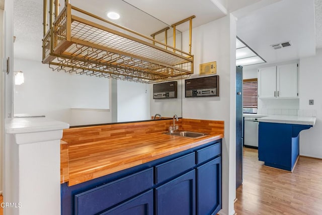 kitchen featuring blue cabinets, sink, stainless steel dishwasher, and white cabinets