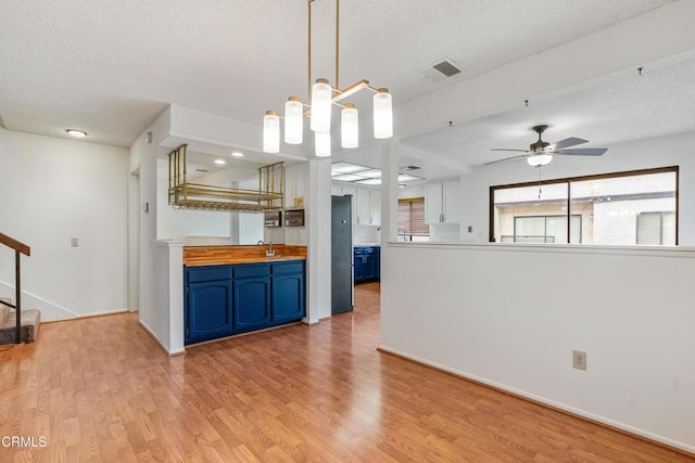 kitchen with blue cabinetry, light hardwood / wood-style floors, and a textured ceiling