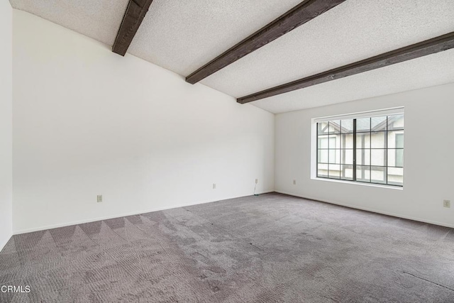 empty room with a textured ceiling, beamed ceiling, and carpet flooring