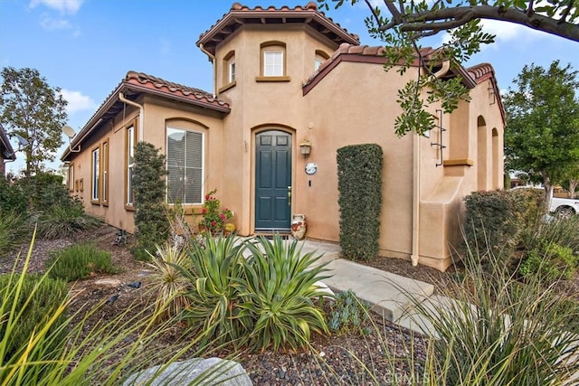 mediterranean / spanish home with stucco siding and a tiled roof