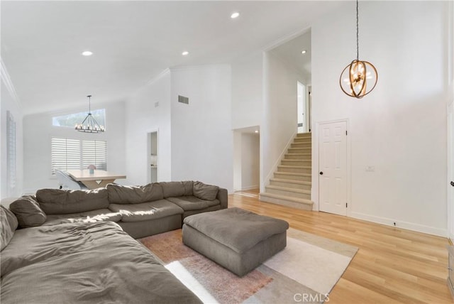 living room with ornamental molding, a chandelier, high vaulted ceiling, and light wood-type flooring