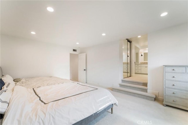 bedroom featuring connected bathroom and light colored carpet