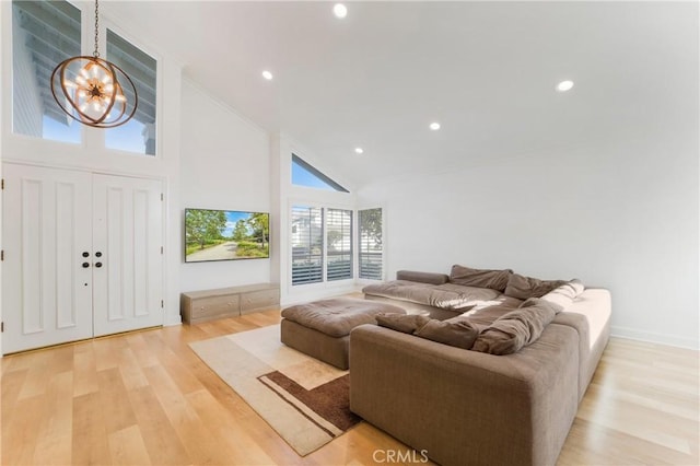 living room with a notable chandelier, light hardwood / wood-style floors, and high vaulted ceiling