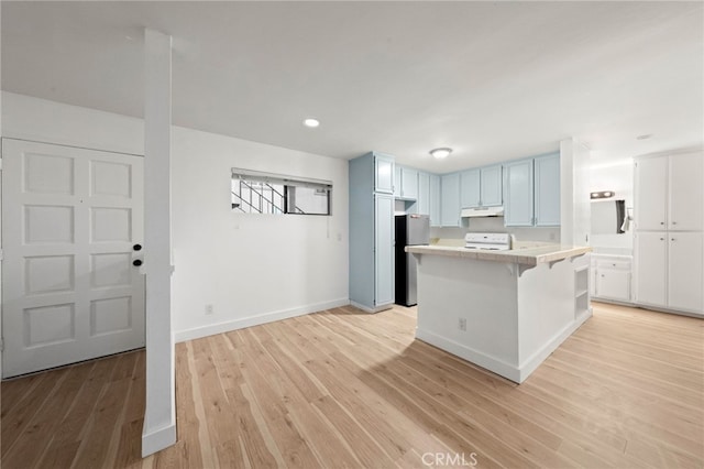 kitchen with light hardwood / wood-style flooring, a breakfast bar area, stainless steel refrigerator, a center island, and range with electric stovetop