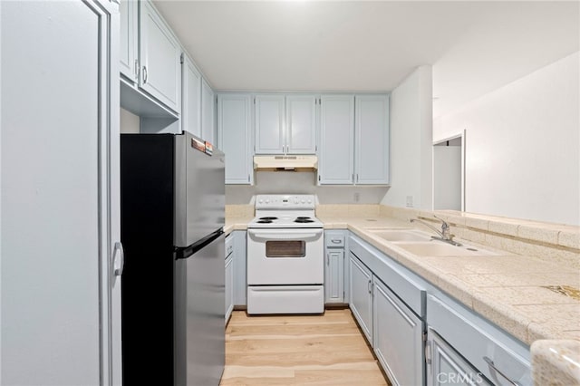 kitchen with sink, stainless steel fridge, light wood-type flooring, and electric stove