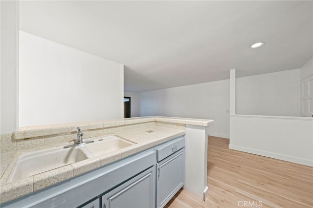 kitchen featuring gray cabinetry, sink, light hardwood / wood-style flooring, and kitchen peninsula