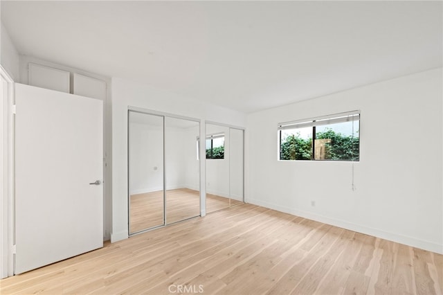 unfurnished bedroom with two closets and light wood-type flooring