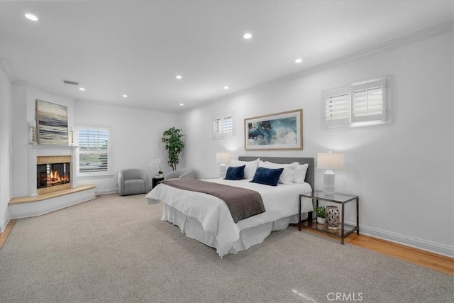 bedroom featuring ornamental molding, a multi sided fireplace, and light hardwood / wood-style flooring