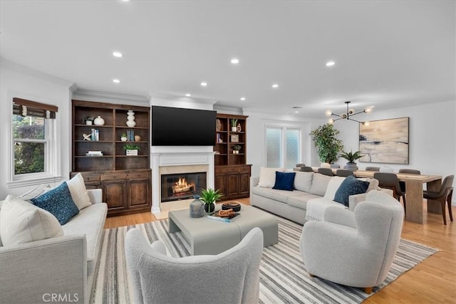 living room featuring crown molding, a healthy amount of sunlight, a high end fireplace, and light wood-type flooring