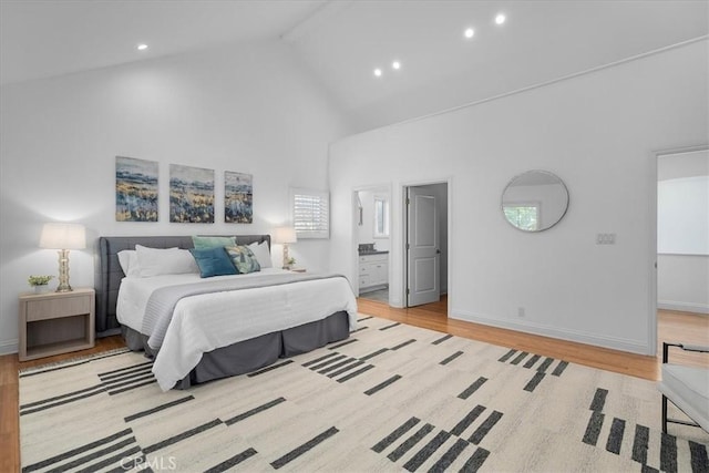 bedroom featuring beamed ceiling, ensuite bathroom, high vaulted ceiling, and light hardwood / wood-style floors