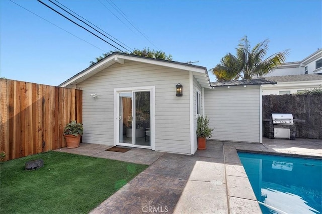 back of house featuring a fenced in pool, an outbuilding, and a patio