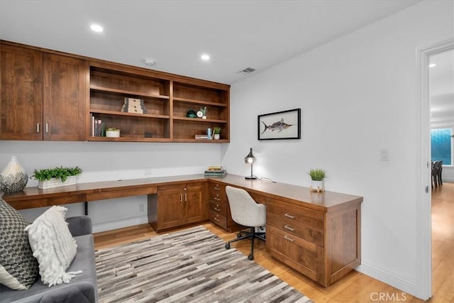 office with built in desk and light hardwood / wood-style flooring