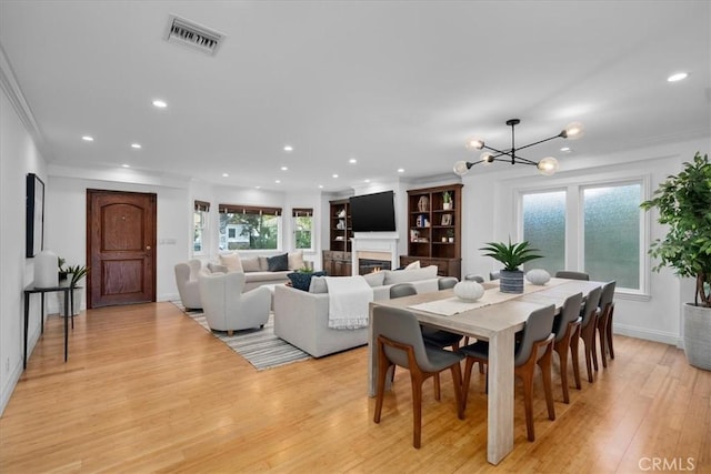 dining room featuring ornamental molding, a chandelier, and light hardwood / wood-style floors