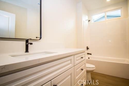 full bathroom featuring vanity, hardwood / wood-style floors,  shower combination, and toilet