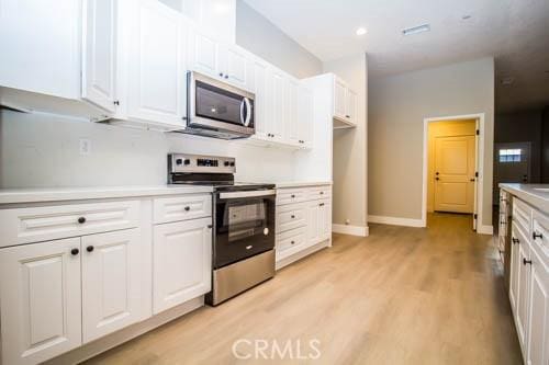 kitchen featuring white cabinetry, appliances with stainless steel finishes, and light wood-type flooring