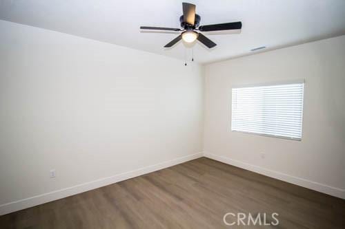 spare room with dark hardwood / wood-style flooring and ceiling fan