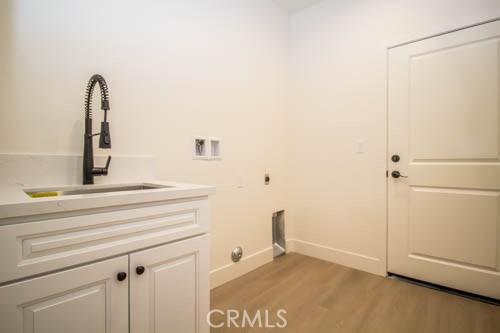 washroom featuring sink, electric dryer hookup, hookup for a washing machine, cabinets, and light hardwood / wood-style floors