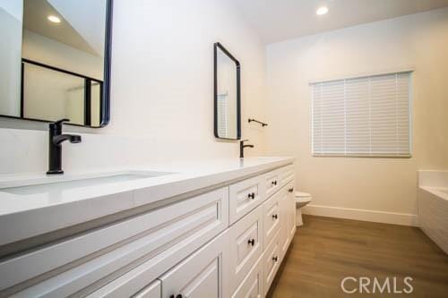 bathroom with vanity, toilet, hardwood / wood-style floors, and a washtub