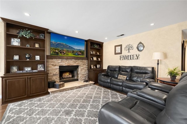 living room with light hardwood / wood-style flooring, a fireplace, and built in shelves