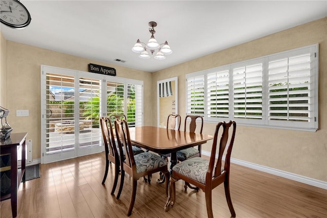 dining area with hardwood / wood-style floors and a chandelier