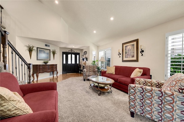 living room featuring plenty of natural light, high vaulted ceiling, a textured ceiling, and light wood-type flooring