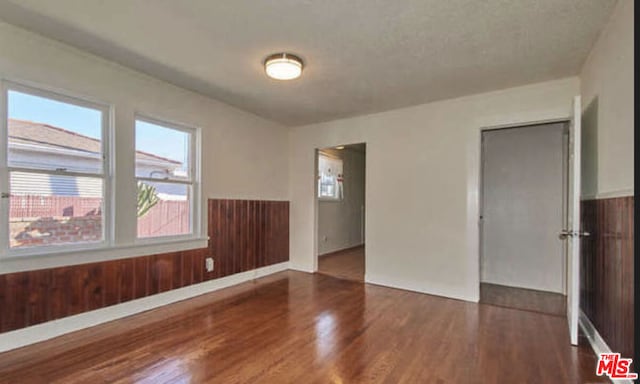 unfurnished room featuring dark wood-type flooring and wooden walls